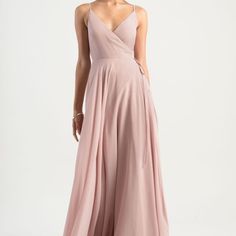 a woman in a long pink dress is looking back at the camera and she has her hands on her hips