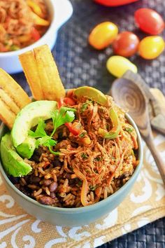 a bowl filled with rice, beans and vegetables next to other foods on a table