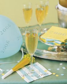 a table topped with glasses of champagne and confetti next to a blue balloon