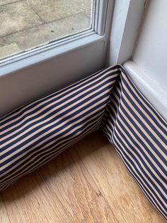 the corner of a window sill with a blue and white striped pillow on it