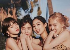 four young women posing for a photo in front of palm trees and the sun shining on them