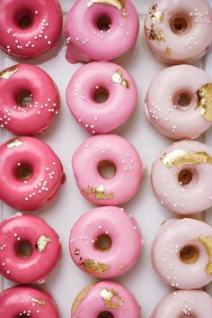 a box filled with lots of pink and yellow donuts covered in sprinkles