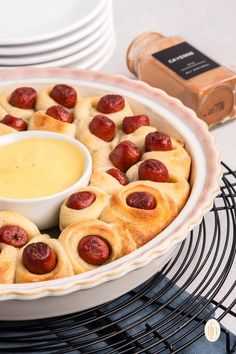 a dish with hot dogs and dip in it on a cooling rack next to plates