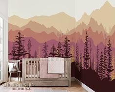 a baby's room with mountains and trees painted on the wall, along with a crib