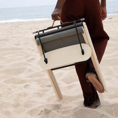 a man carrying a chair on the beach