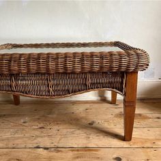 a wicker bench sitting on top of a wooden floor