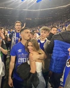 two people hugging each other in front of an audience at a sporting event with fans