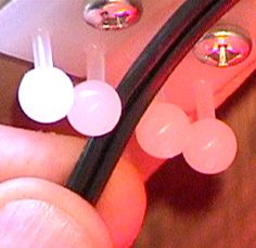 a person holding a cell phone with two ear plugs attached to the back of it