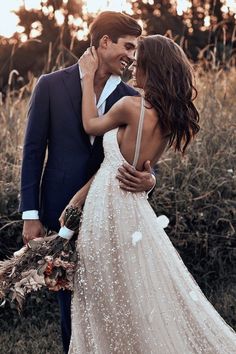 a man in a suit and woman in a wedding dress are hugging each other outside