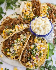 shredded meat tacos with corn, cilantro and rice on a white plate