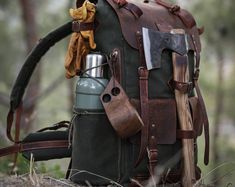 an old backpack with leather straps and tools on the back is sitting in the woods