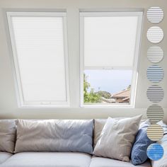 a white couch sitting under two windows in a living room next to a wall with circles on it