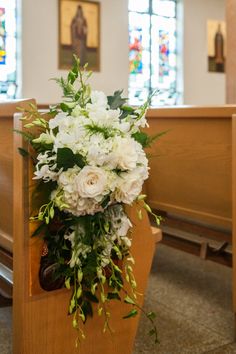 white flowers and greenery decorate the pews of a church