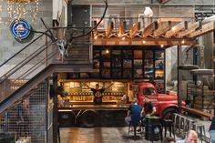 people are sitting at tables in an industrial building with exposed ceilings and lights hanging from the ceiling