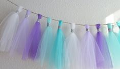 several different colored tulle skirts hanging from a line on a wall with white and blue trim