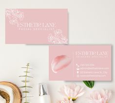 two business cards sitting on top of a table next to pink flowers and greenery