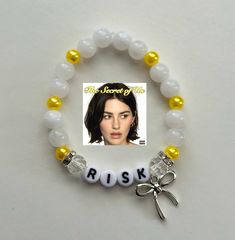 a white bracelet with yellow beads and a photo of a woman's face on it