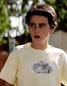 a young boy making a face while holding a tennis racquet