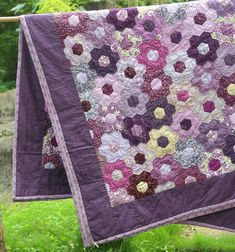 two quilts hanging on a clothes line in the grass