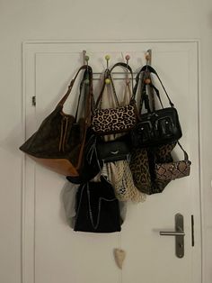 a bunch of purses are hanging on the wall next to a door with hooks