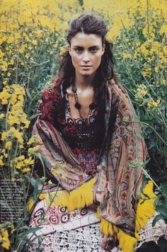 a woman is sitting in the middle of a field full of yellow wildflowers