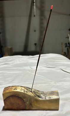 a piece of wood with a stick sticking out of it sitting on top of a bed