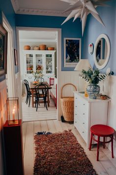 a living room with blue walls and white furniture in the center, along with a rug on the floor