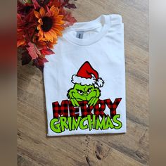 a white t - shirt with the words merry grinmas on it next to a sunflower