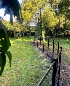 a fenced in area with grass and trees