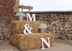 hay bales are stacked with letters and flowers on top of each other in front of a brick wall