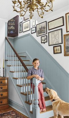 a young boy sitting on the stairs next to a dog and looking up at him