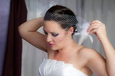 a woman wearing a veil and holding her hair in one hand while looking at the other