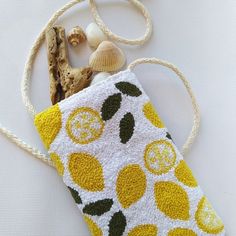 a yellow and white bag with lemons on it sitting next to a seashell