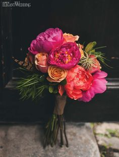 a bouquet of flowers sitting on top of a stone floor next to a black door