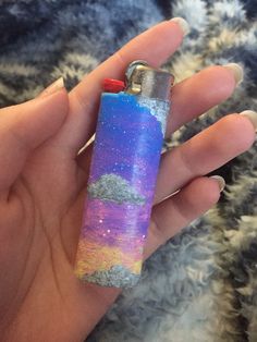 a person holding a lighter in their hand with the sky and stars painted on it