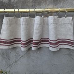 the curtain is hanging on a metal rod with two red and white striped linens