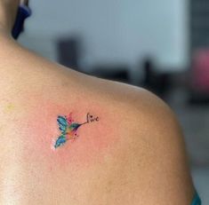 the back of a woman's shoulder with a small tattoo on it