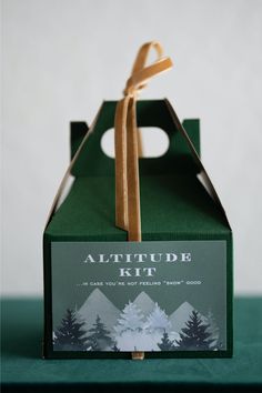 a green box with a brown ribbon tied around it and an ad for altitude kit