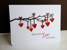 a card with red hearts hanging from a tree branch