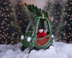 a baby in a green car with a christmas tree on top