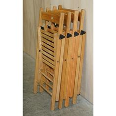 a stack of wooden chairs sitting on top of a cement floor next to a wall