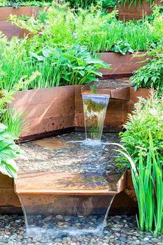 a water fountain surrounded by plants and rocks