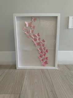 a white frame with pink paper butterflies in it