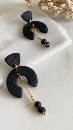 the black and gold earrings are hanging from chains