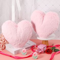 two pink heart shaped pillows sitting on top of a table next to flowers and ribbon