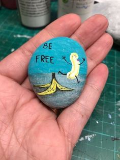 a hand holding a painted rock that says be free