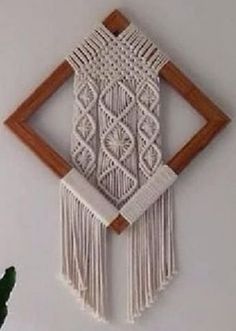 a white wall hanging with wooden frame and tassels