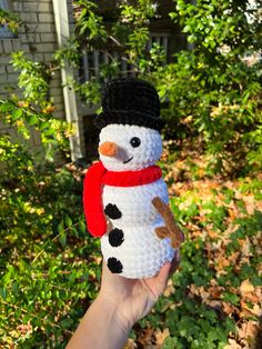 a crocheted snowman with a black hat and red scarf