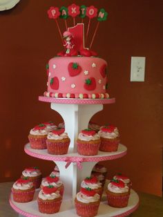 a three tiered cake with cupcakes on it