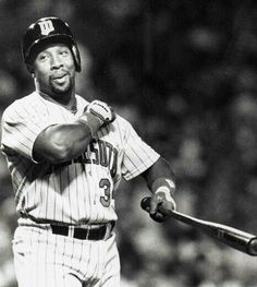 a black and white photo of a baseball player holding a bat in his hand while smiling